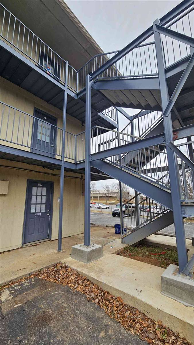 New concrete footings poured under the painted steel columns of an apartment staircase