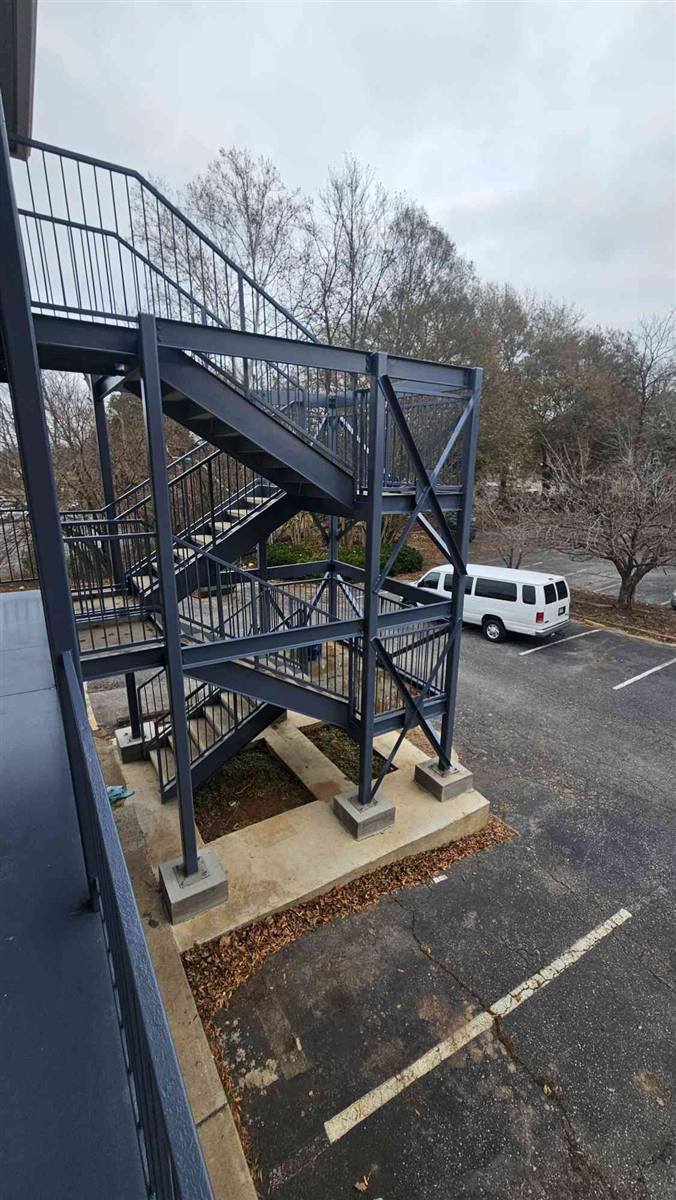 Three-story steel staircase repainted, standing on new concrete footings